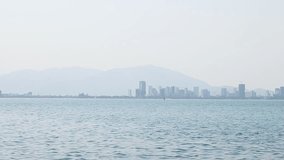 City on horizon in fog above blue sea water panning motion. Skyline landscape in mist and blue azure water of ocean. Nice scenery landscape sea panorama. Beautiful background of sea scenery. Ocean.