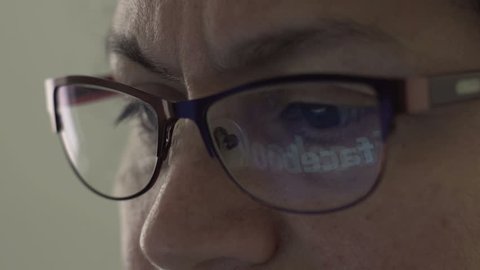 HALLE, GERMANY - APRIL 25, 2017: Reflection of Facebook Logo in the lens of the glasses of a middle age woman.