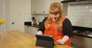 4K Happy extrovert plus size woman having a video chat at home, talking to a young child & pulling funny faces. Slow motion.