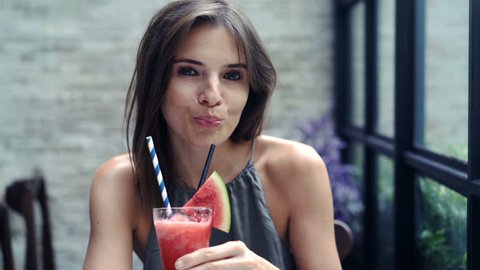 Beautiful woman raising toast to camera and drinking juice in cafe, 4K
