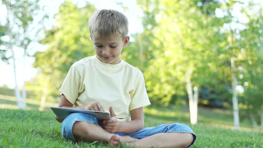 Boy using a tablet computer outdoors

