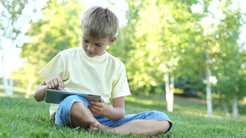 Boy using a tablet computer outdoors. Thumbs up. Ok
