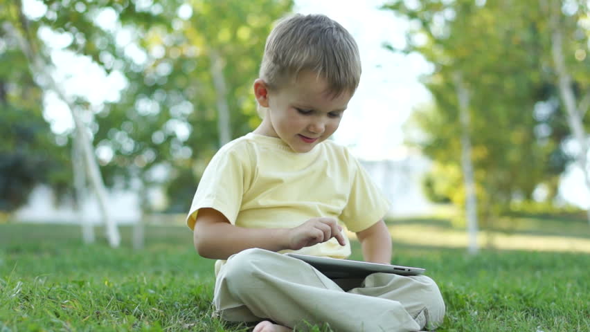 Little boy using a tablet computer outdoors. Thumbs up. Ok
