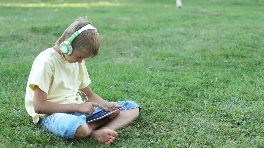 Boy listening music through headphones using a tablet PC
