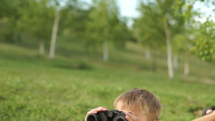Boy with binoculars lying on the grass
