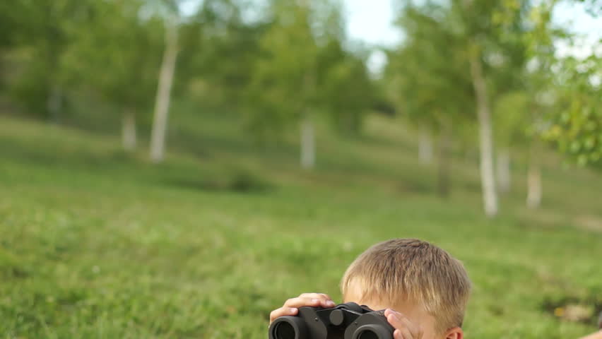 Boy with binoculars lying on the grass
