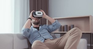 Caucasian male in casual clothes using his VR headset indoors, watching 360 video at home. 4K UHD RAW edited footage 