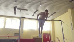 Gymnast exercises on high horizontal bar HD slow-motion video. Athlete training gymnastics skills and performing giant elements, handstand, somersault