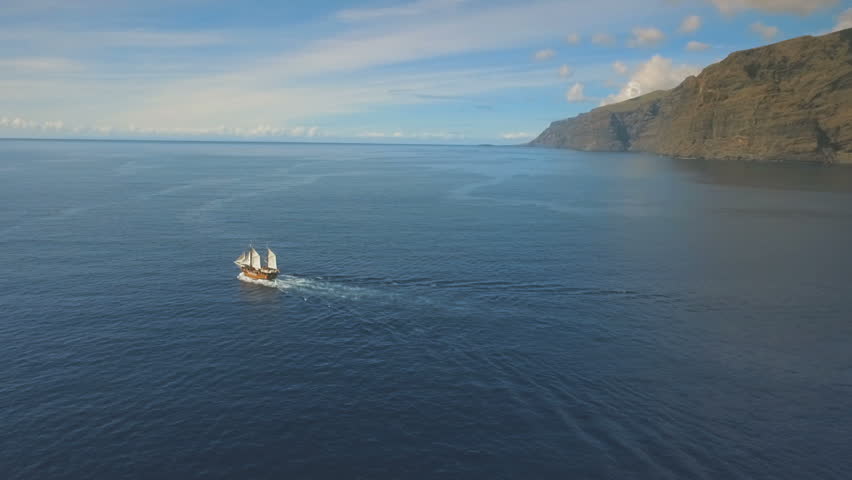 Pirate ship sails along the lonely island at sunset
