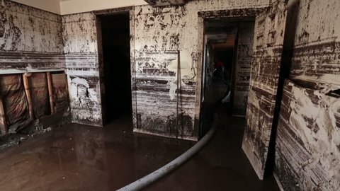 FOUNTAIN GREEN, UTAH 30 JUL 2012: Man walks in home house flood with water and mud from flash flood. Wildfire burned vegetation rain caused surge of muddy ash water that completely filled the home.