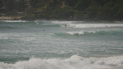 Long shot of surfers riding waves at greenmount on the gold coast of Queensland, Australia.