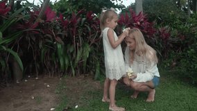 Little girl decorates her mother's hair with flowers of Plumeria slow motion stock footage video