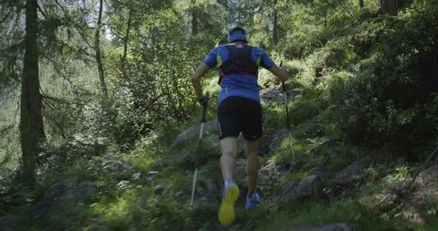 caucasian trail runner running in mountain through woods, villages. 4k gimbal wide back video shot