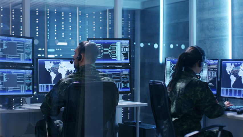Male and Female Military IT Technicians Working on Computers with Multiple Displays Showing Various Information. Possible Surveillance, Army Maneuvers. Shot on RED EPIC-W 8K Helium Cinema Camera.