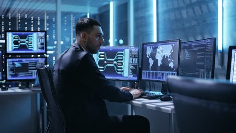 Technical Controller/ Operator Working Between Workstations with Multiple Displays. Possible Power Plant/ Airport Dispatcher/ Government Surveillance/ Shot on RED EPIC-W 8K Helium Cinema Camera.