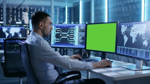 Technical Controller/ Operator Working at His Workstation with Multiple Displays (Green Screen Mock-up). Possible Power Plant/ Airport Dispatcher/ Dam Worker/ Government Surveillance/ Space Program.