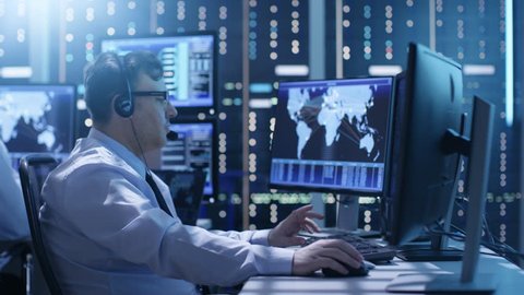 Professional Technical Support Personnel Working in a System Control Center. We See Many Working Displays with Various Data Visible on Them. Shot on RED EPIC-W 8K Helium Cinema Camera.