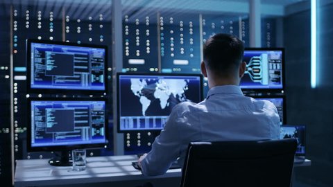 Technical Controller Working at His Workstation with Multiple Displays. Displays Show Various Technical Information. He's Alone in System Control Center.  Shot on RED EPIC-W 8K Helium Cinema Camera.