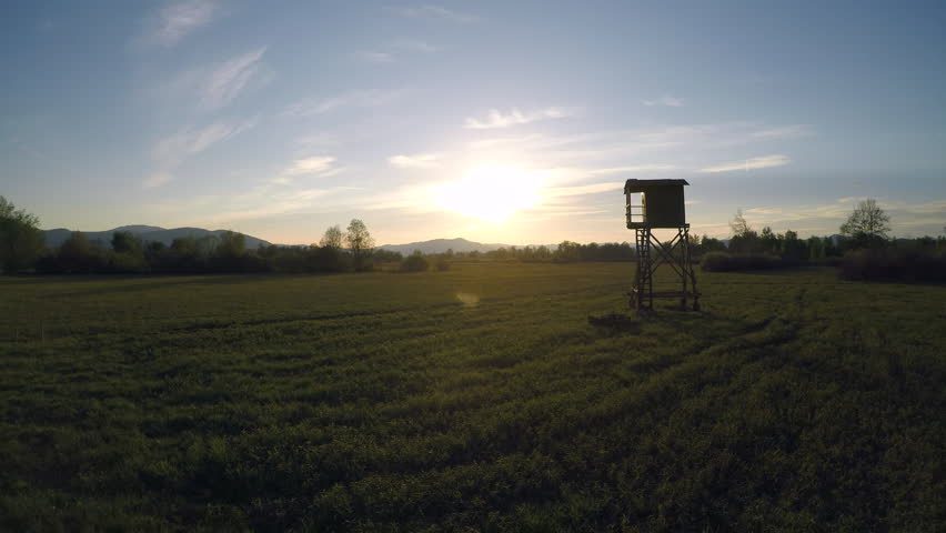 4K AERIAL Wildlife observation tower in the meadow at sunset