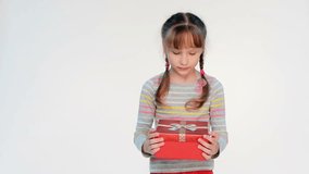 Little girl opening her gift feeling surprised embracing a box with happiness, locked down real time video
