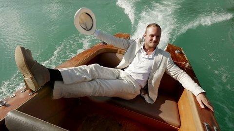 lifestyle portrait of young happy man relaxing on boat enjoying life after business success