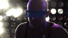 Closeup face of handsome man in blue leg glasses dancing at the party over disco lights background - video in slow motion