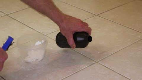 Scrubbing Grout in a Bathroom Tile Floor
Male hand scrubbing grout in a bathroom floor with hydrogen peroxide and baking soda. Brush cleaning floor grout with natural baking soda and hydrogen peroxide