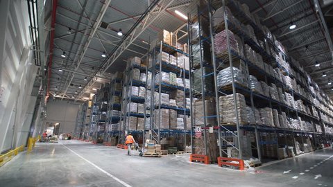 Industrial warehouse with boxes. Forklift Small cargo truck drives to warehouse. Large warehouse logistics terminal. Person worker walking in big storehouse. Interior mail Industry. Wide shot 4k