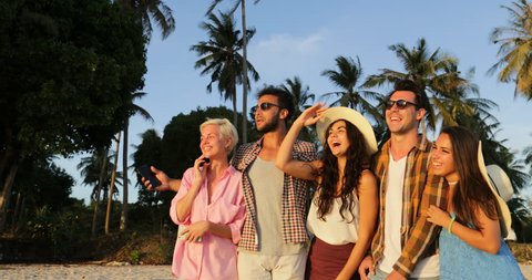 People Group Talking Take Selfie Photo On Cell Smart Phones At Sunset Under Palm Trees, Happy Smiling Man And Woman Friends Slow Motion 60