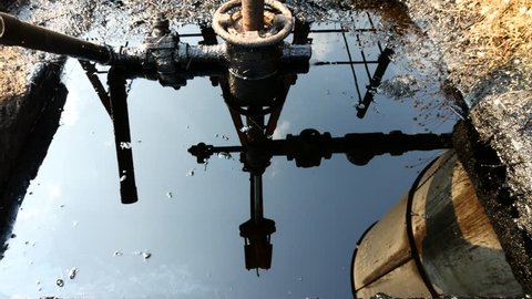 Reflection of Close up Oilfield Christmas Tree and Oil Pump Jack (Sucker Rod Beam) in the oilfield in Fang province, Thailand. 
