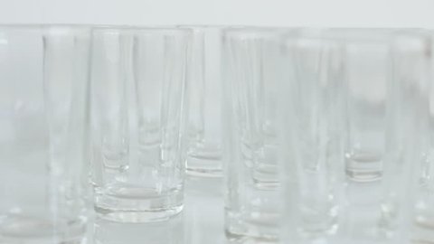 Shot glasses on white background close-up 4K 2160p 30fps UltraHD tilting footage - Transparent spirits or liquor drink glass slow tilt 3840X2160 UHD video