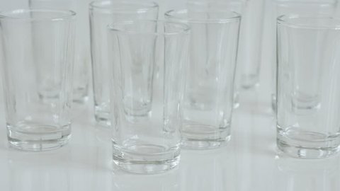 Tilting on transparent spirits or liquor drink glass 4K 2160p 30fps UltraHD footage - Close-up of shot glasses on white background slow tilt 3840X2160 UHD video