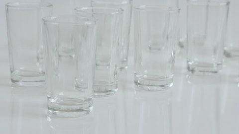 Many transparent spirits or liquor drink glasses 4K 2160p 30fps UltraHD footage - Close-up of shot glass on white background slow tilt 3840X2160 UHD video