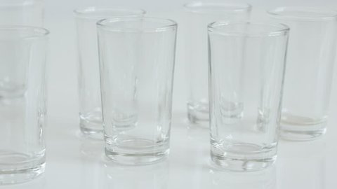 Slow tilt shot glass on white background  close-up 4K 2160p 30fps UltraHD footage - Many transparent spirits or liquor drink glasses 3840X2160 UHD tilting  video