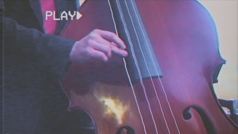 Fake VHS tape: medium - close up shot of a musician playing a double bass.
