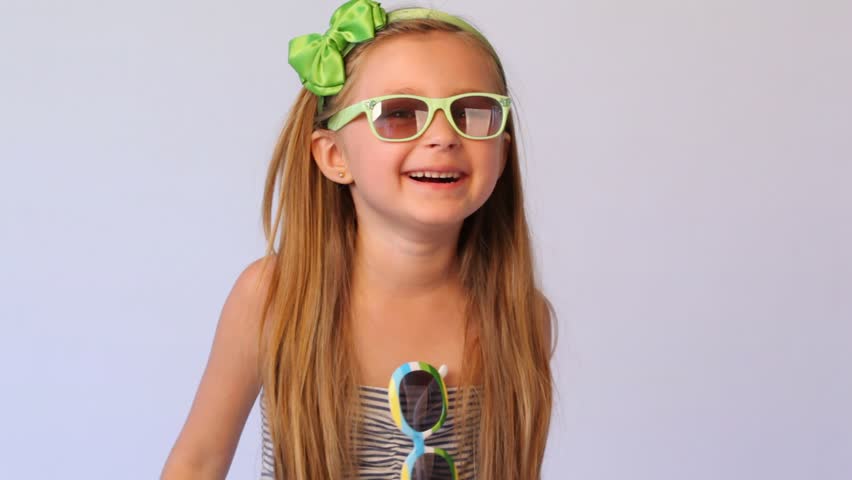 little girl wearing spectacles on face and on dress holds in each hand on spectacles