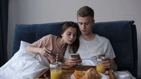Couple sharing phone watching media content in bed