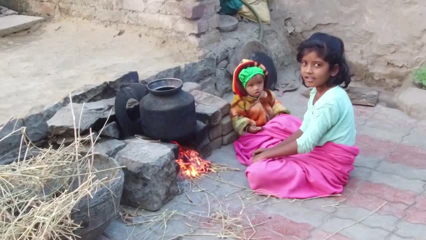 Two girls getting warm front of Hearth in winter season early morning rural village Salunkwadi, Ambajogai, Beed, Maharashtra, India, South East Asia.