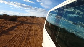 Driving in the red sands of the Kalahari Desert in Namibia. Stabilized video looking backwards, car is visible.