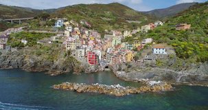 aerial view of travel landmark destination Riomaggiore, a small mediterranean sea town, Cinque terre National Park, Liguria, Italy. Morning with sun and clouds. 4k aerial drone orbit video shot