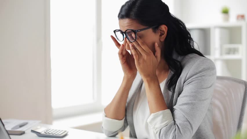 Business, overwork, deadline, vision and people concept - tired businesswoman in glasses working with laptop computer at office and rubbing eyes | Shutterstock HD Video #26311778