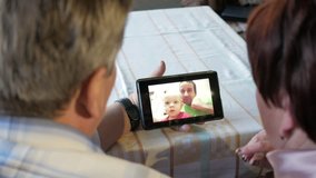 An elderly couple communicates with their grandchild by video linking the tablet. A man and a woman are talking to relatives.