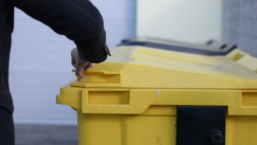 Hand of man throwing away small cardboard box in big waste container for recycling | Shutterstock HD Video #26313692