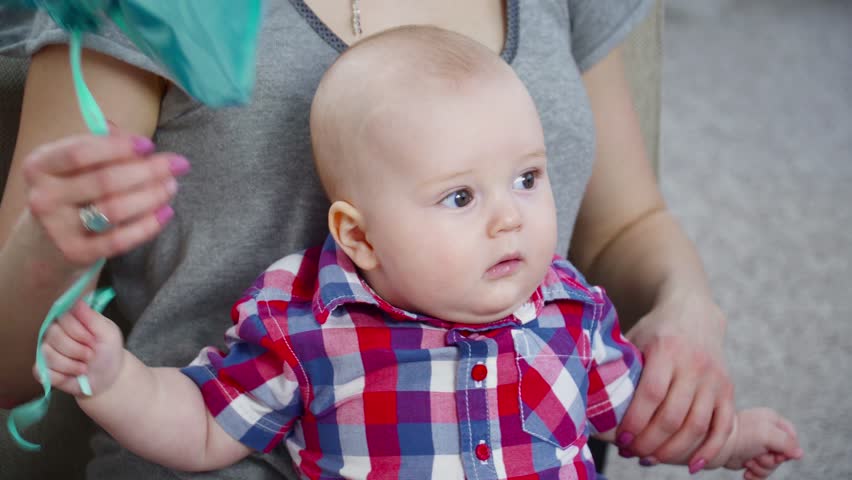 Young mother playing with her 6 months old son with baloons closeup