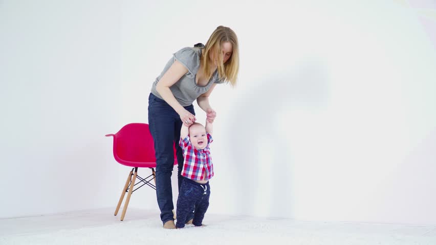 Young mother halping her 6 months to make first steps