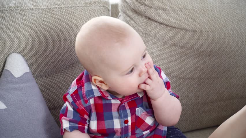 Small cute baby boy inthe shirt sitting on sofa closeup