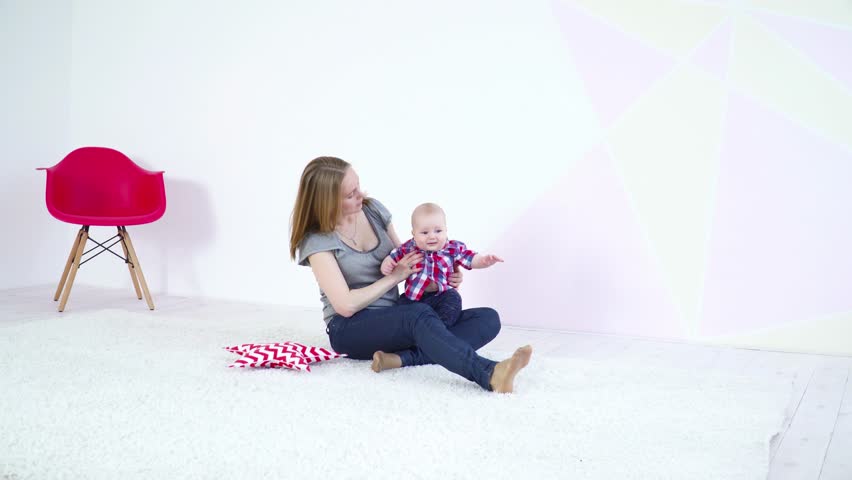 Young mother playing with her 6 months son on carpet