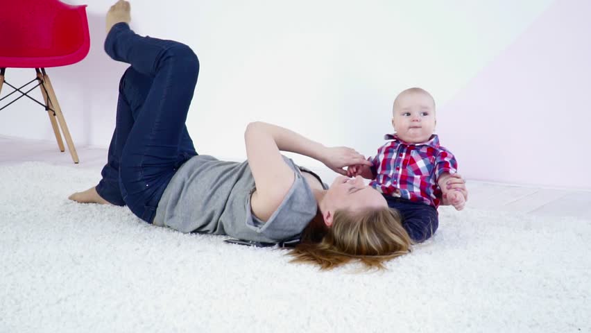 Young mother laying on carpet playing with her son slow motion