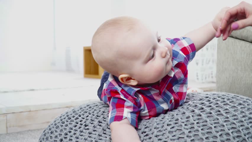 Mother helping 6 months baby boy to turn