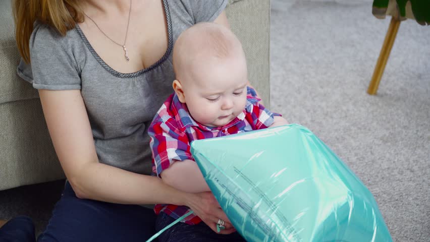 Young mother playing with her 6 months old son with the baloons on floor